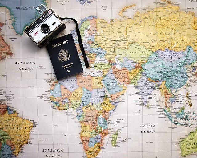 Vintage camera and a United States passport placed on a detailed world map featuring continents and oceans.